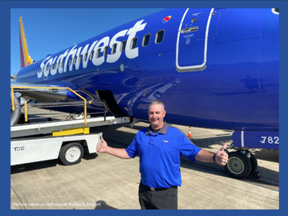 Bryan Foster standing by  a commercial airplane  