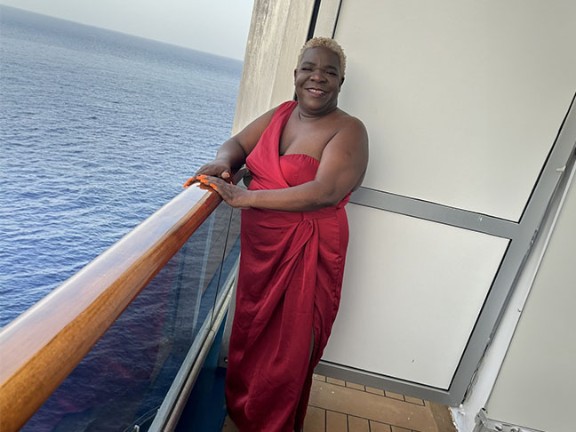 Kim Denkins posing near a balcony by the coast. 