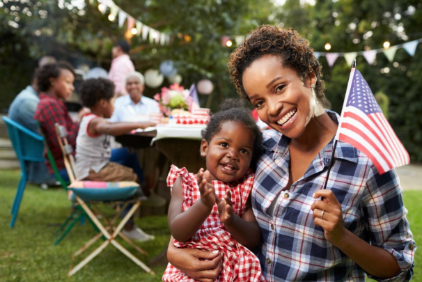 Mother and daughter wave American flag at a summer picnic 