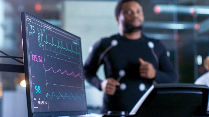 A man runs on a treadmill while a screen displays information about his heart