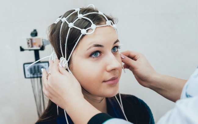 A doctor uses an electroencephalogram to track electrical activity in a girl's brain
