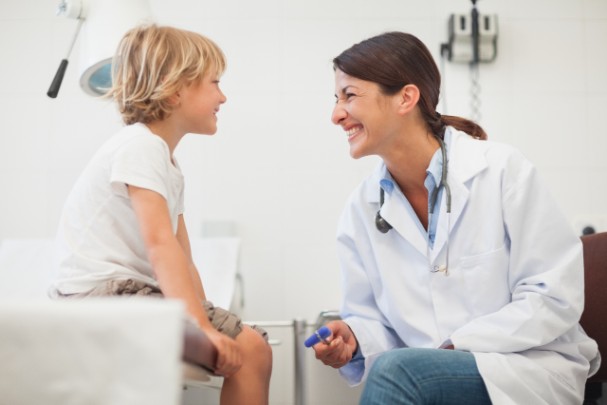 A doctor sits with a young boy during a sports physical