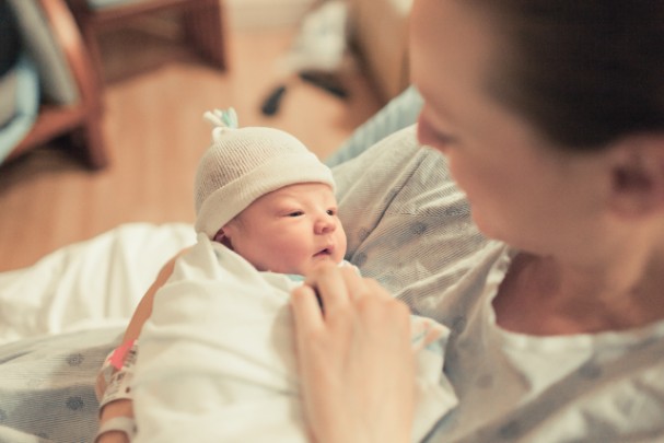 A woman holds her infant in her arms. 