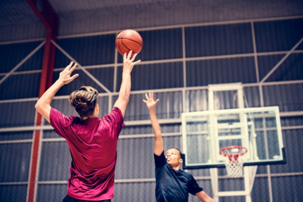 Two teenage boys play basketball on an indoor court