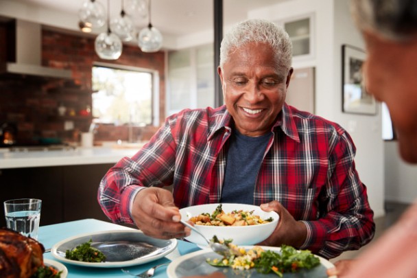 A man fills his plate with vegetable and other healthy foods.