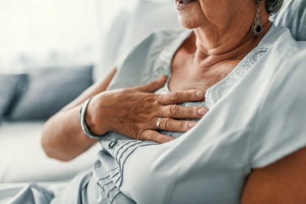 An older woman clutches her chest as she experience pain 