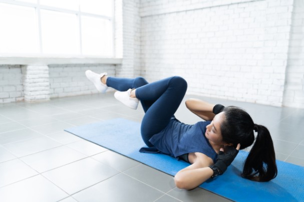 Woman lays on yoga mat and exercises