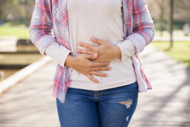 A woman clutches her abdomen in pain.