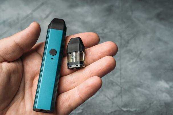 A person holds an e-cigarette, or vape, and its cartridge. 