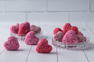 Red and pink heart-shaped truffles sit on a counter.  