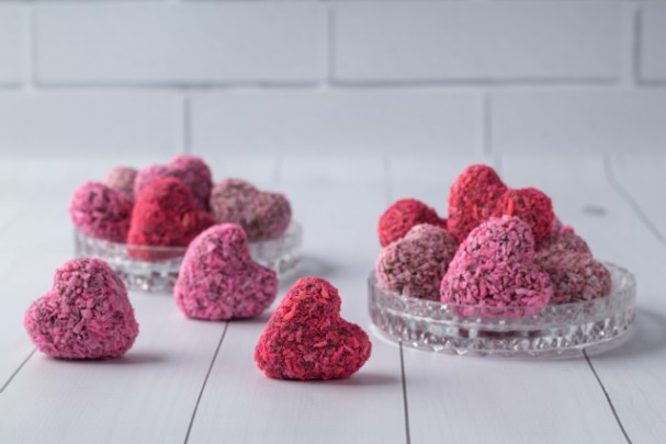 Pink and red candy hearts made from chocolate sit on a counter. 