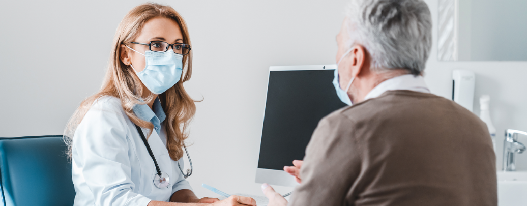 Female doctor wearing face mask speaking to male patient wearing face mask