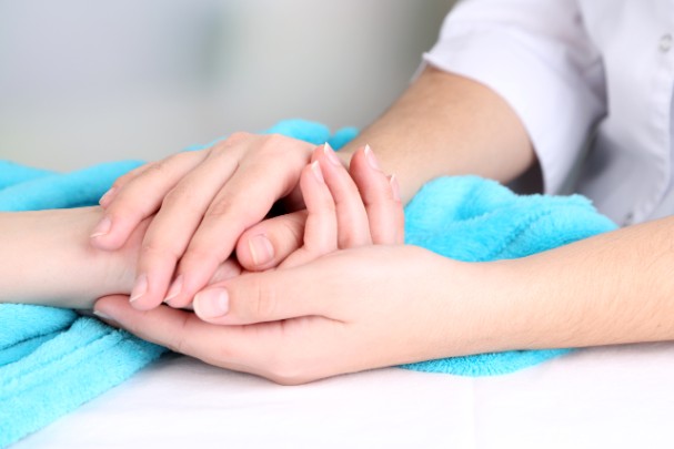 Two people hold hands in a compassionate moment on top of a blue blanket
