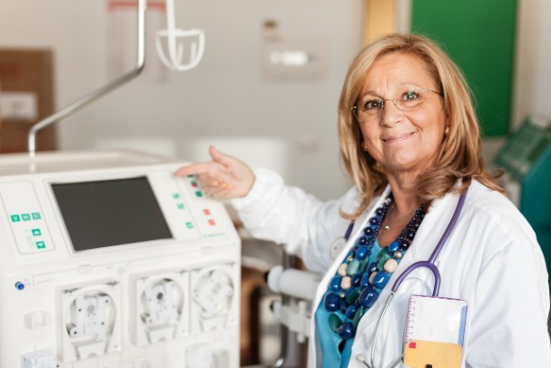 A doctor points to a dialysis machine. 