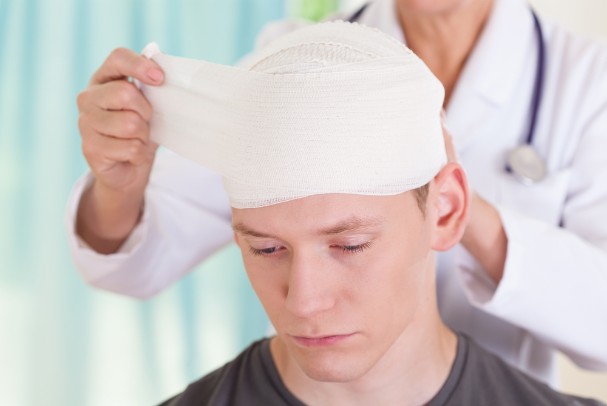 Doctor wraps young man's head in gauze following a head injury 