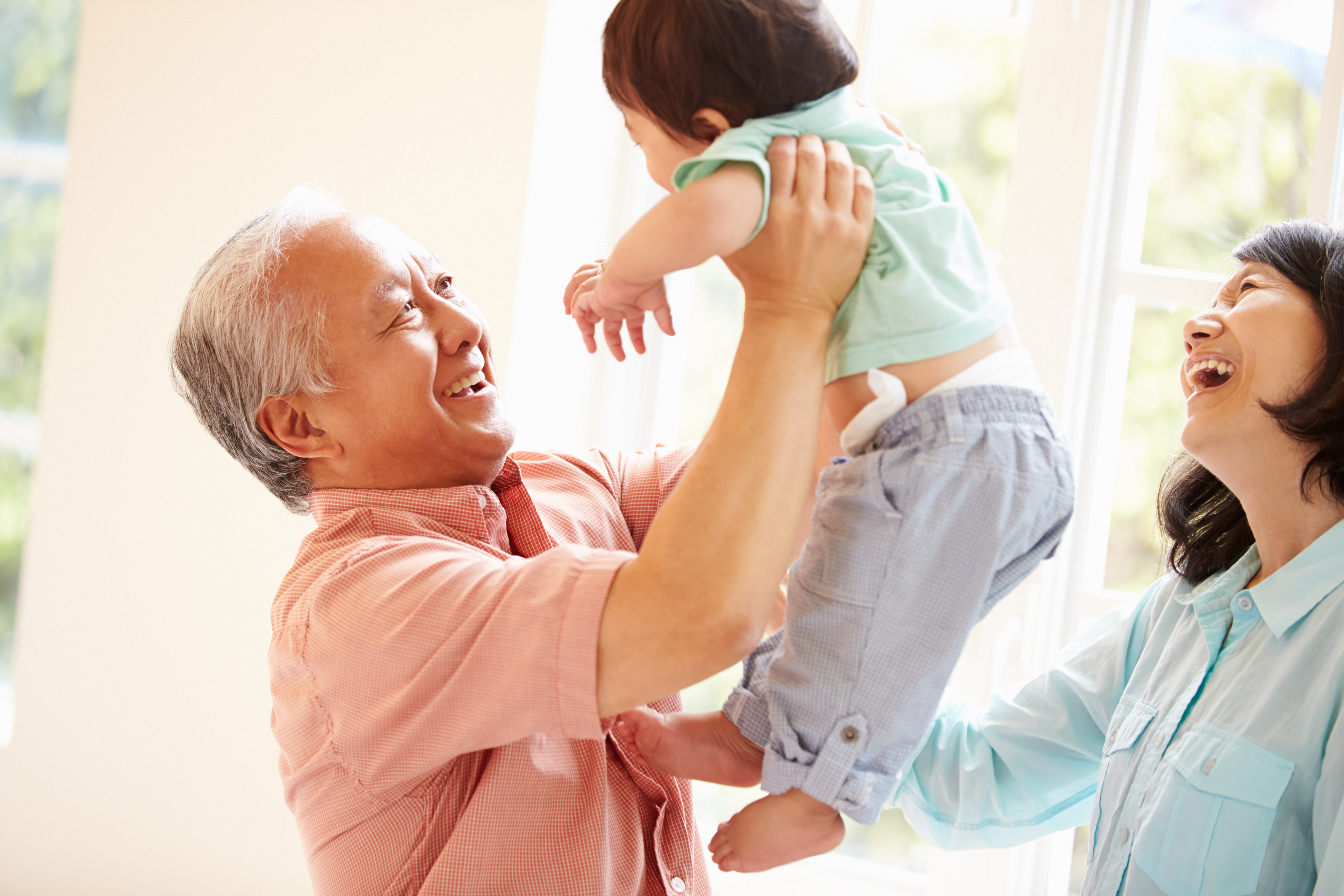 Elderly couple lift up and smile at their grandchild