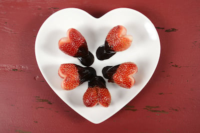 alt="Heart-shaped, chocolate-dipped strawberries sit in a circle on a plate. "