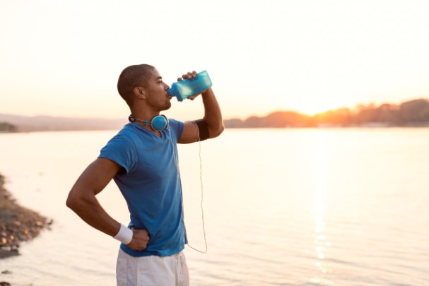 A young man pauses his run to drink water 