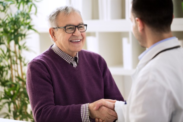 An elderly man smiles at his doctor 