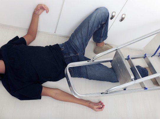 A man lies on floor after falling off of a ladder