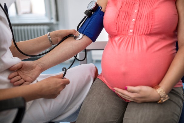 A doctor uses a blood pressure cuff to measure a pregnant woman's blood pressure