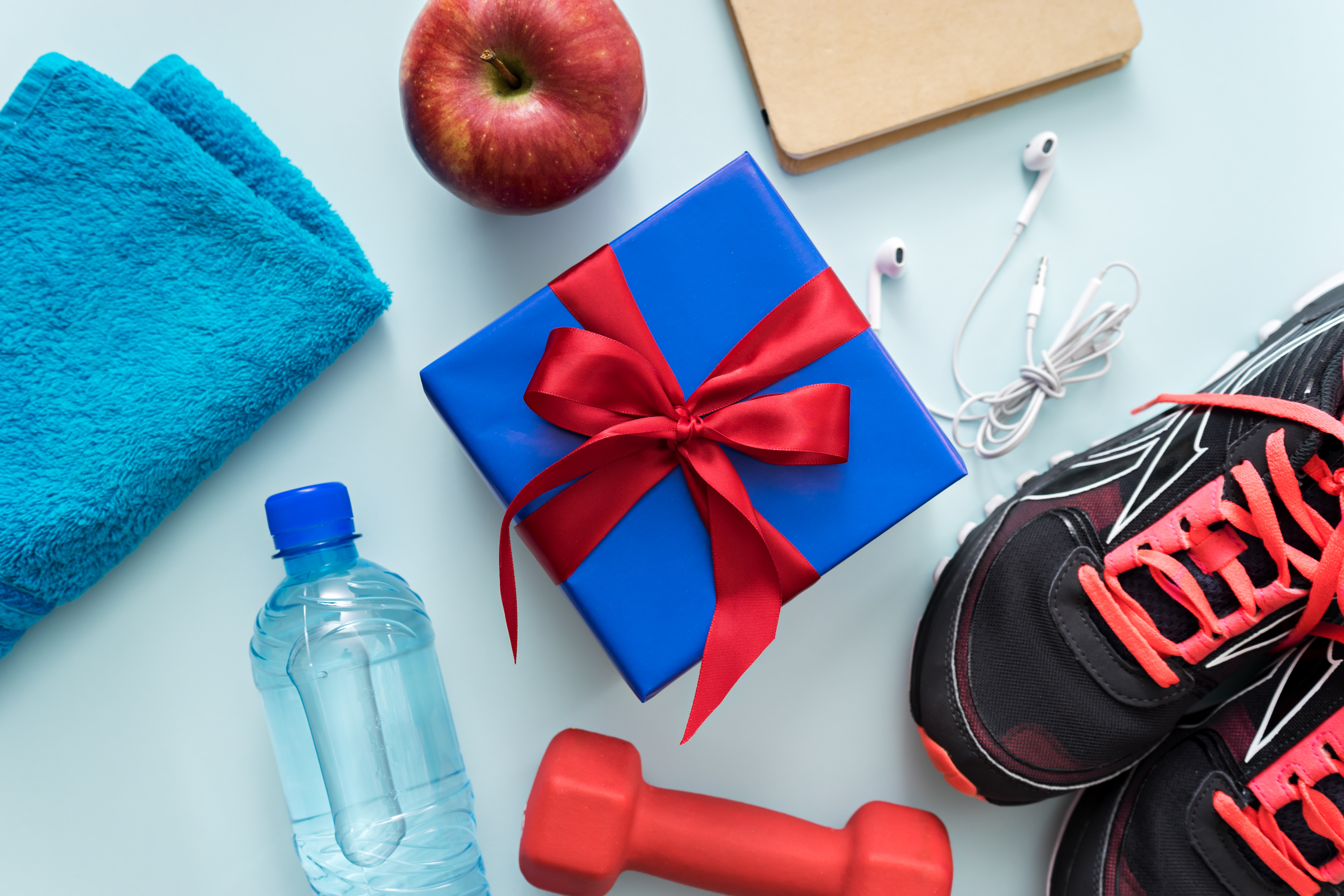 A present sits next to fitness equipment, including sneakers, weights, and headphones.