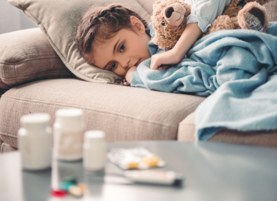 Girl lying on couch sick next to table with antibiotics