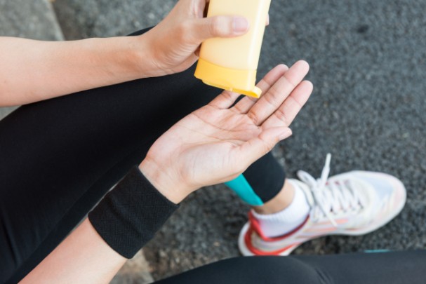 A person squeezes sunscreen into their hand 