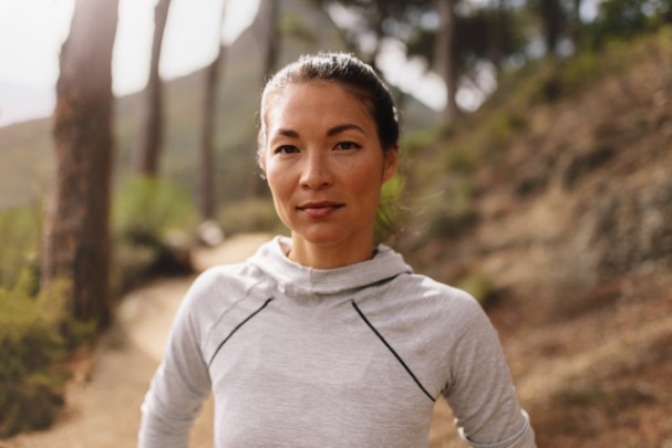 A woman stands in the middle of a trail in the woods. 