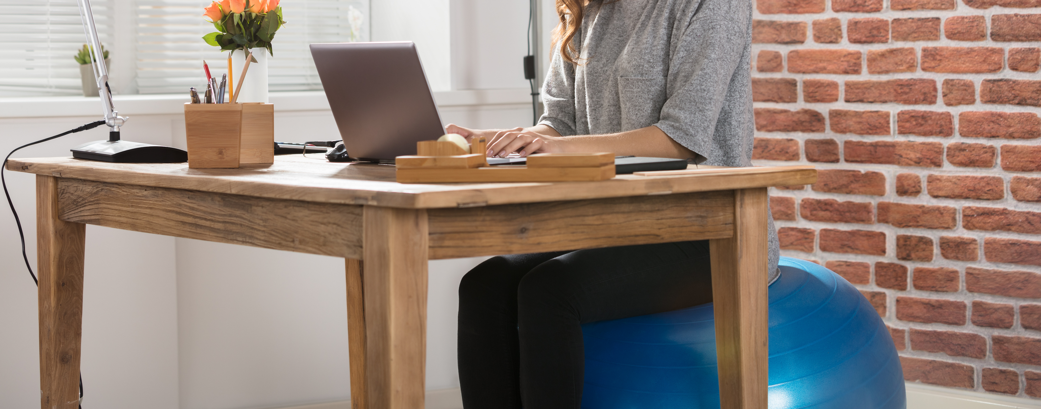 Woman working at desk while using exercise ball