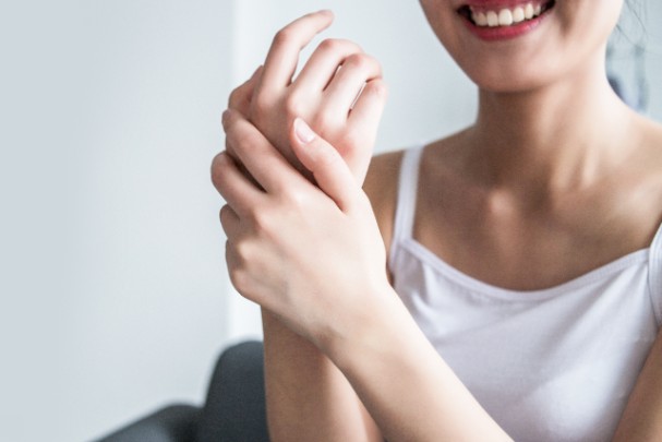 A woman smiles as she touches her clear skin 