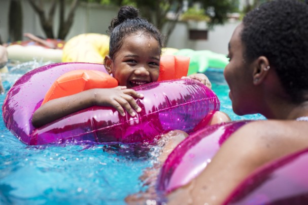 A young girl and her mother float in tubes in a pool 