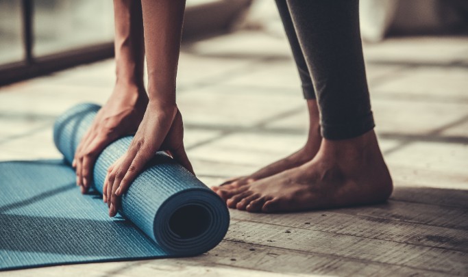A woman unrolls her yoga mat 