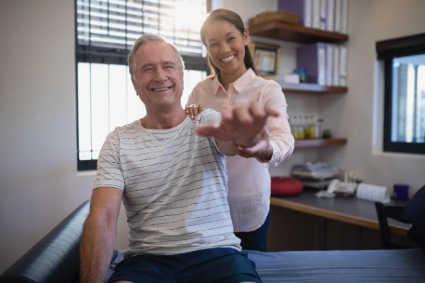 A physical therapist helps a patient extend his arm. 