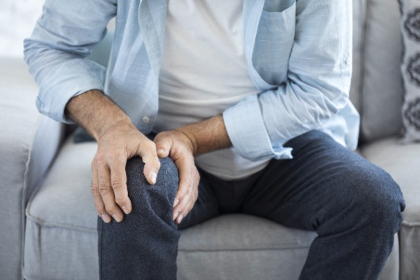 An older man grips his knee in pain 