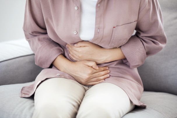 A woman clutches her abdomen in pain 