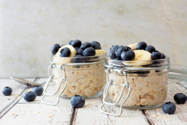Two jars full of oatmeal and topped with blueberries