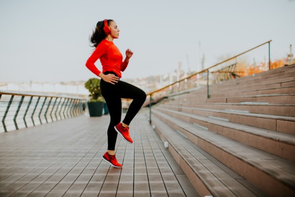 A woman jogs in place in front of a set of stairs 