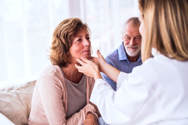 A doctor gently touches a woman's neck so she can feel the thyroid glands