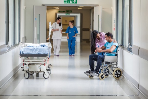 A woman helps a young man in a wheelchair in a hospital