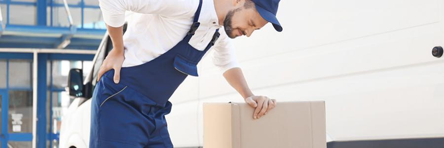 Man experiencing back pain while moving heavy boxes