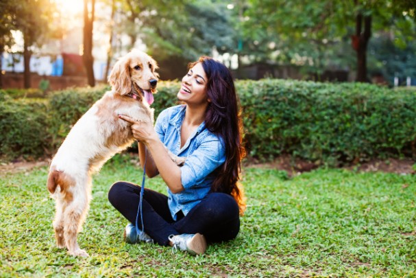 A woman plays with her brown dog in a park. 