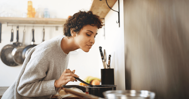 Young woman inhaling scents of her food as part of smell training to get back her sense of smell after COVID-19 illness. 