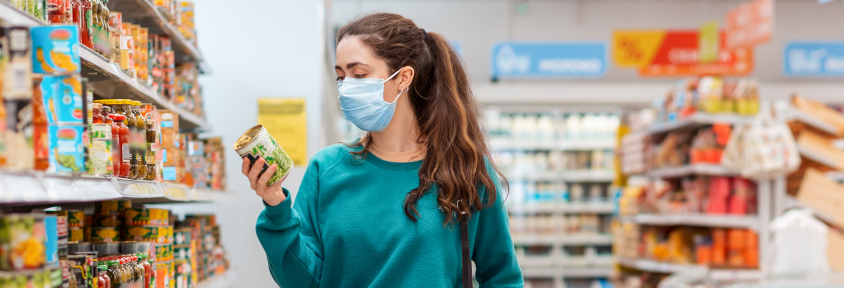 Woman in a grocery store searches for the healthiest canned vegetables.