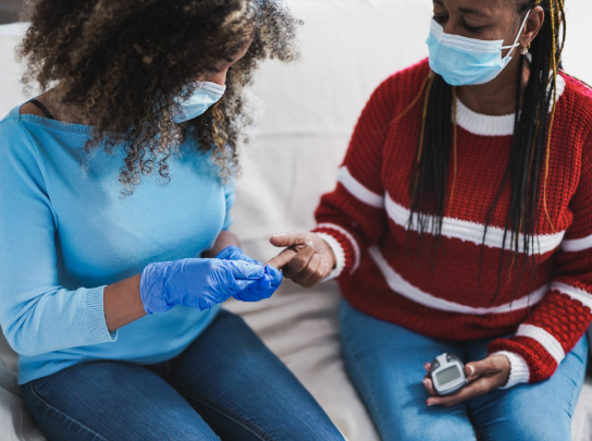 A woman helps her mom measure her blood sugar so she can manage her diabetes and protect her heart.