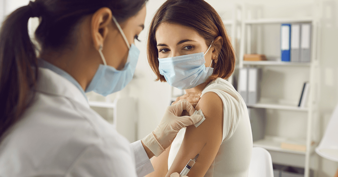 Young female receives her second dose of the COVID-19 vaccine from a healthcare professional. 