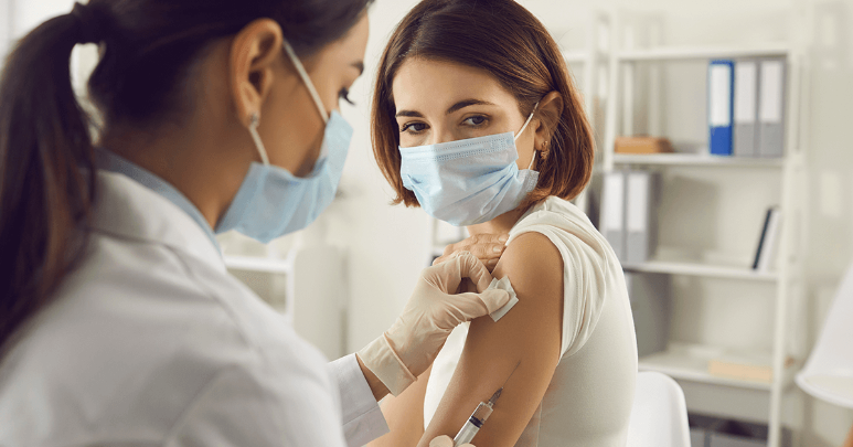 Young female receives her second dose of the COVID-19 vaccine from a healthcare professional. 