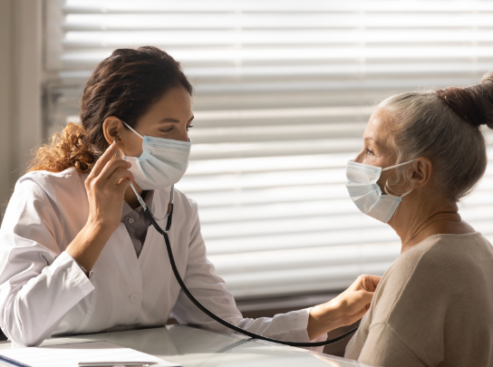 A cardiologist uses a stethoscope to listen to a woman’s heartbeat.