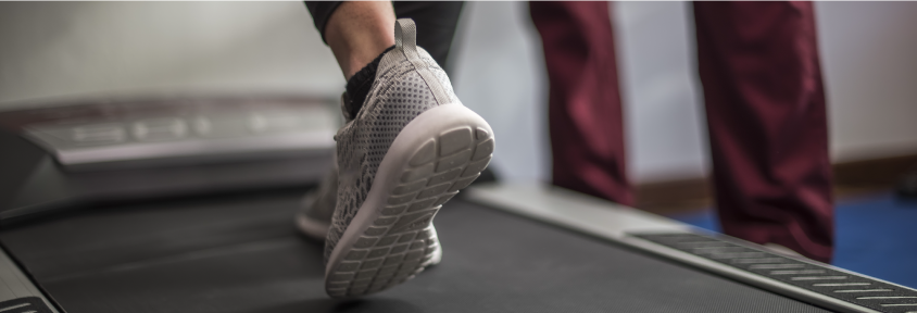 A woman walks on a treadmill as part of a cardiac stress test. 