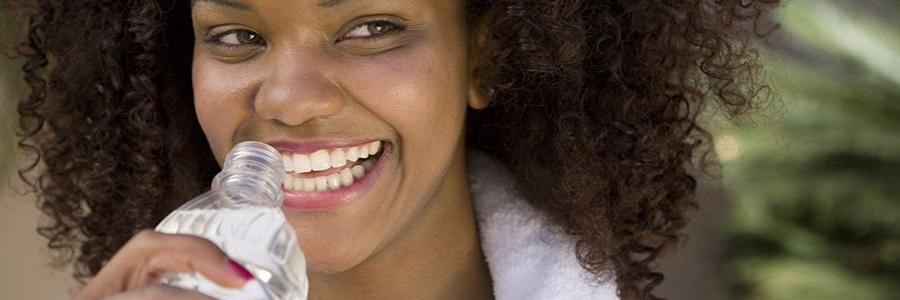 Woman smiling while drinking from a bottle of water